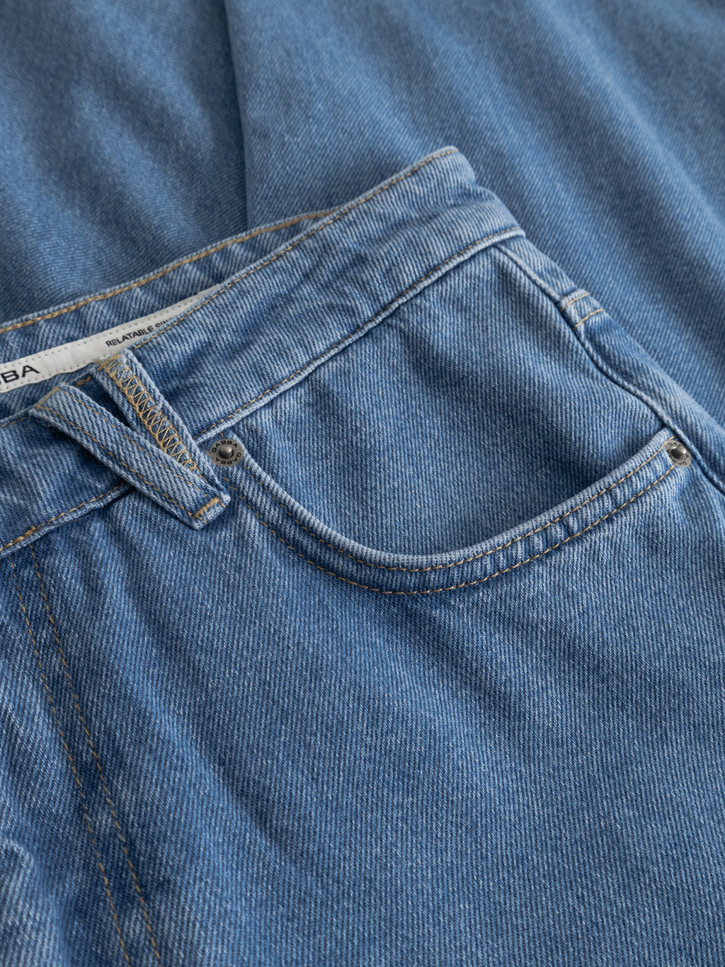 Close-up of Gabba’s GABmarc 5poc Mid Jeans in mid blue denim, showing the front pocket, button, and waistband in durable fabric with additional 5-pocket denim detail in the background.