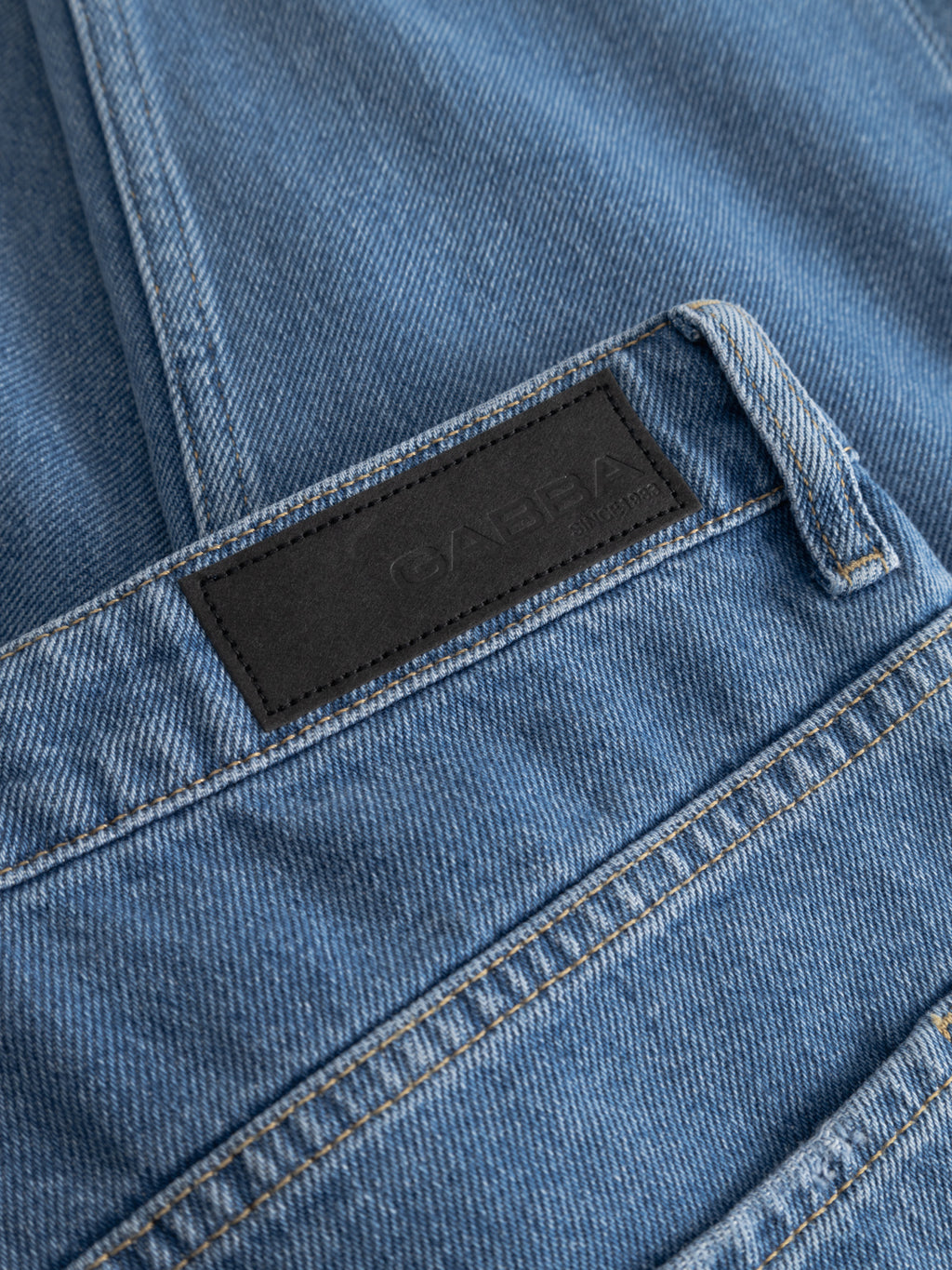 Close-up of Gabba GABmarc 5poc Mid Jeans in mid blue denim, showing a black rectangular leather Gabba patch, visible stitching, belt loops, and classic 5-pocket design.