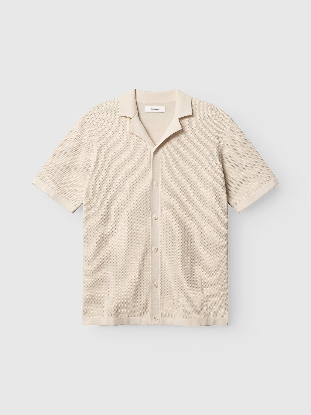 The Gabba GABgeno Resort Bride SS Knit in Birch is a beige, short-sleeve knit shirt with a resort collar, textured open-weave pattern, and relaxed fit, shown on a plain light background.