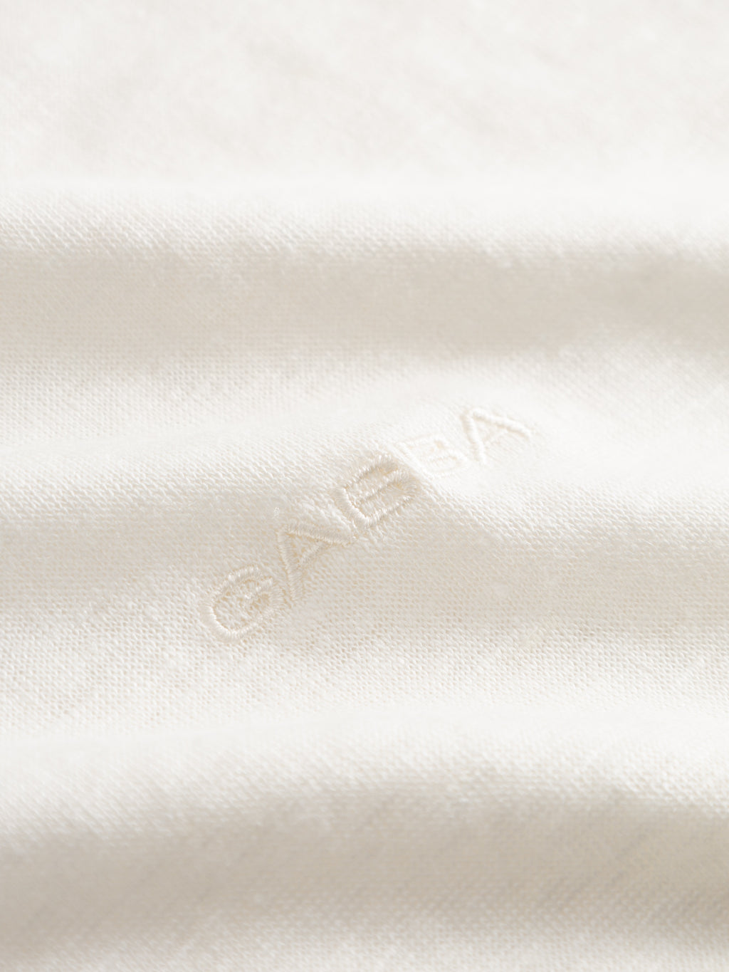 Close-up of the Gabba GABdune Linen SS T-Shirt in Birch, featuring soft, white textured fabric with the Gabba logo subtly embroidered in matching thread. The linen material appears breathable and slightly wrinkled for a relaxed look.
