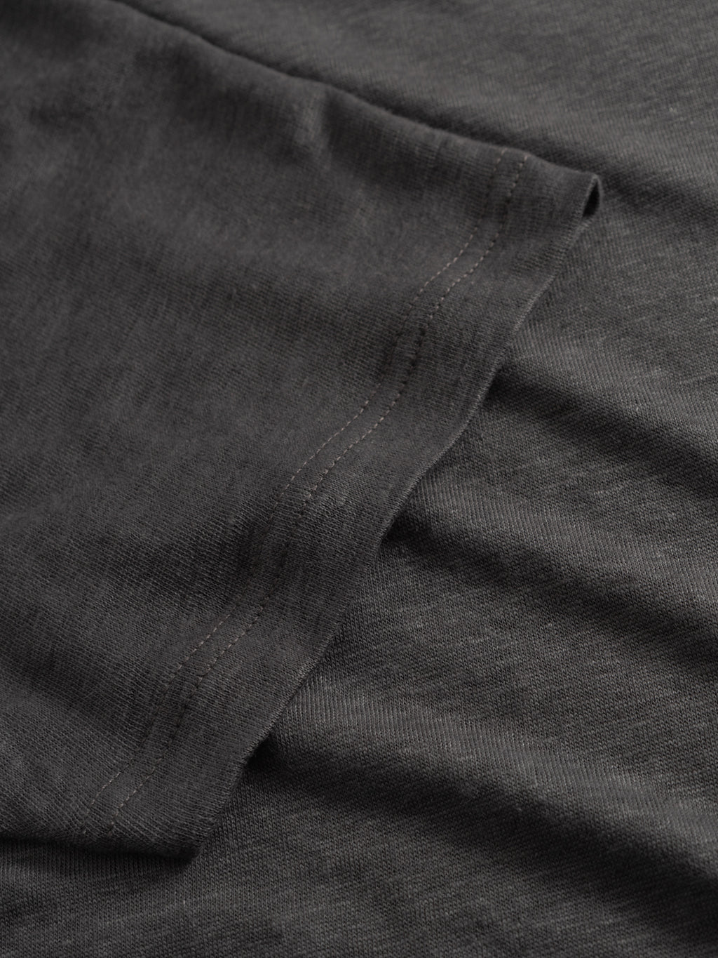 A close-up view of the Gabba GABdune Linen SS T-Shirt in Pirate Black highlights the textured linen fabric and showcases the hemline with visible stitching along the edge.