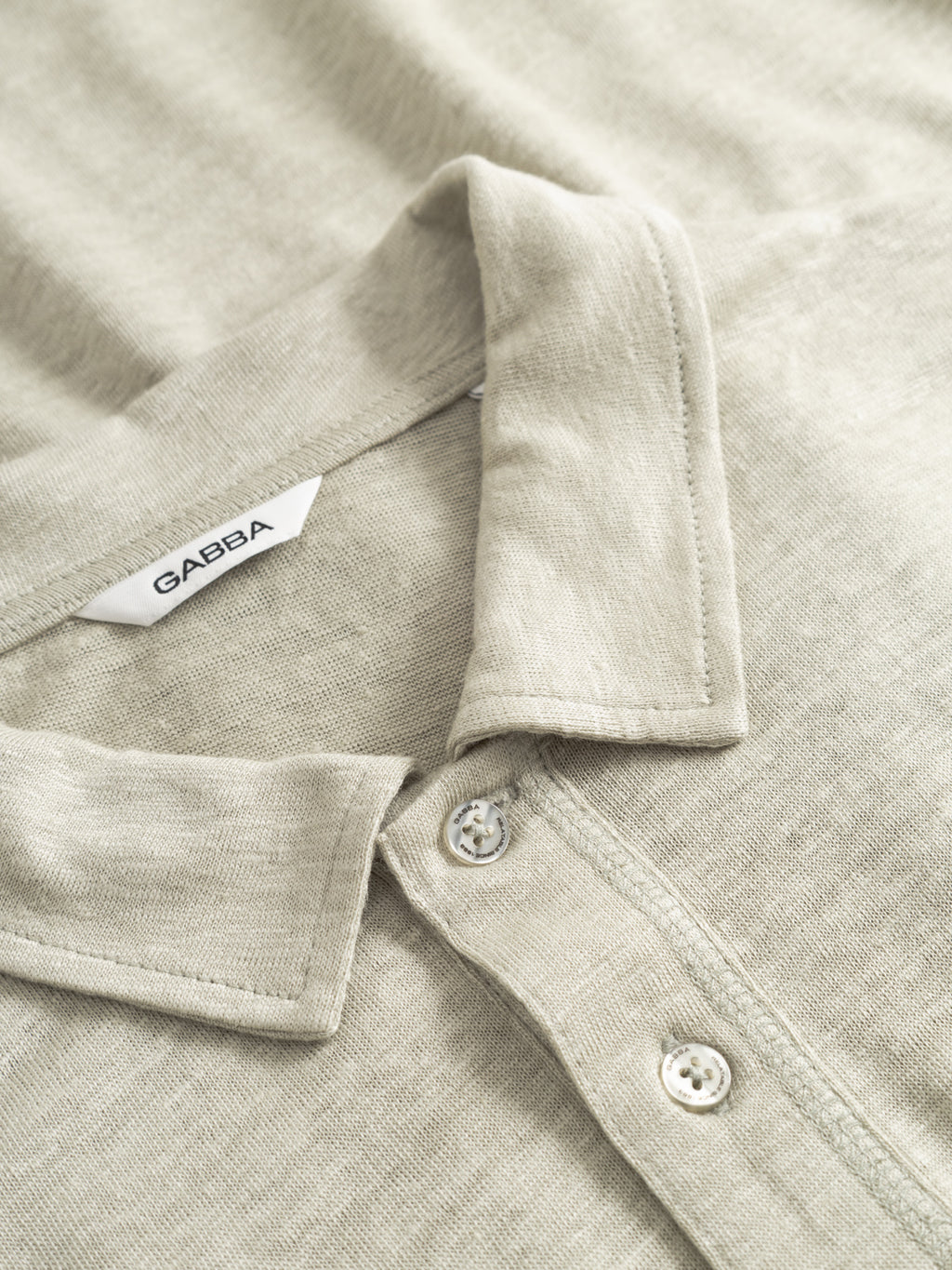 Close-up of the Gabba GABdune Polo Linen SS T-Shirt in Mineral Gray, featuring a folded collar, two buttons, and a white GABBA tag. This regular fit polo blends classic style and comfort for any occasion.