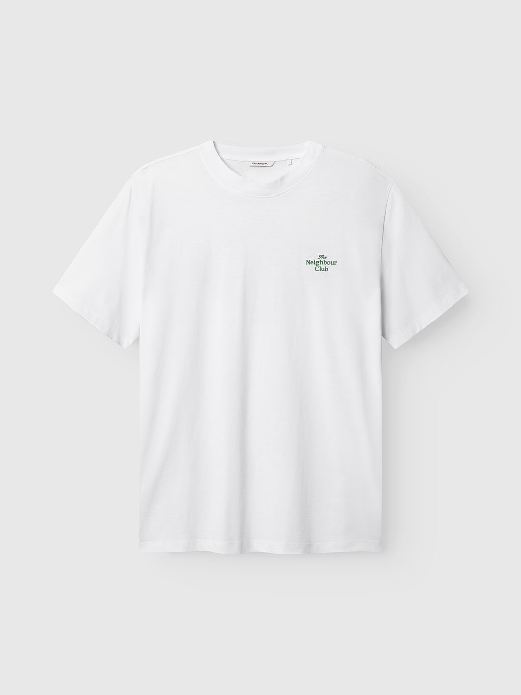 The Gabba GABnigel Boxy NBH SS T-shirt GOTS in white is an oversized organic cotton tee with a small green logo and text on the left chest, shown against a light gray background.