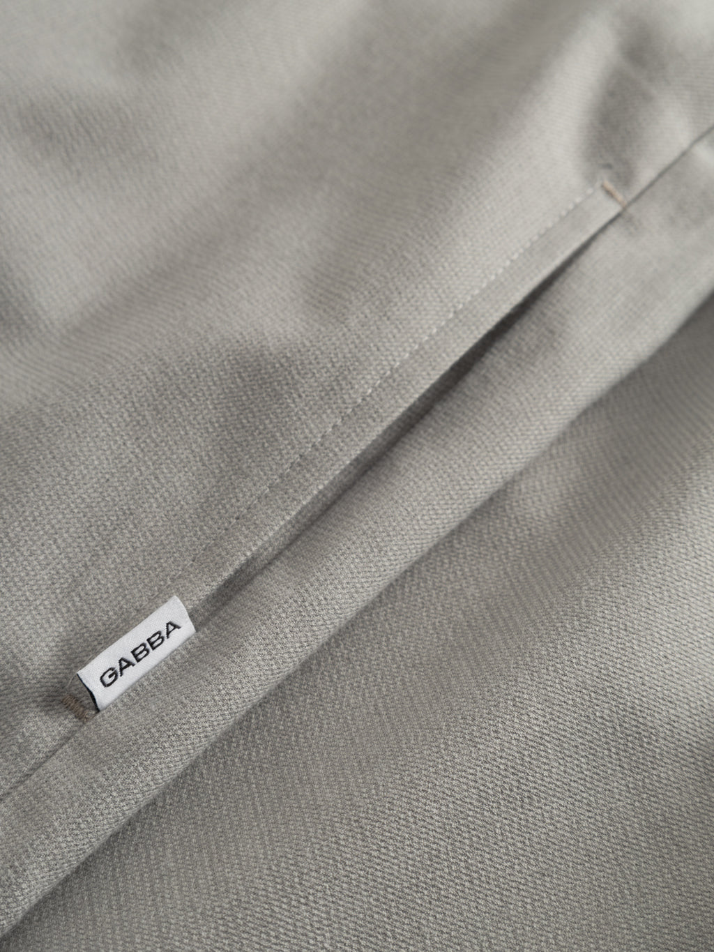 Close-up of the GABtogger Base Deme LS Overshirt in Mineral Gray by Gabba, showing a textured fabric with pocket, white GAERA label, and detailed test stitching that highlights the shirt’s quality craftsmanship.