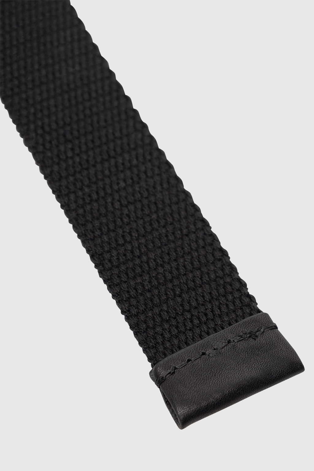 Close-up of the Gabba GABmixme Belt in black, featuring a woven fabric strap and a stitched refined leather end, displayed on a plain light gray background.