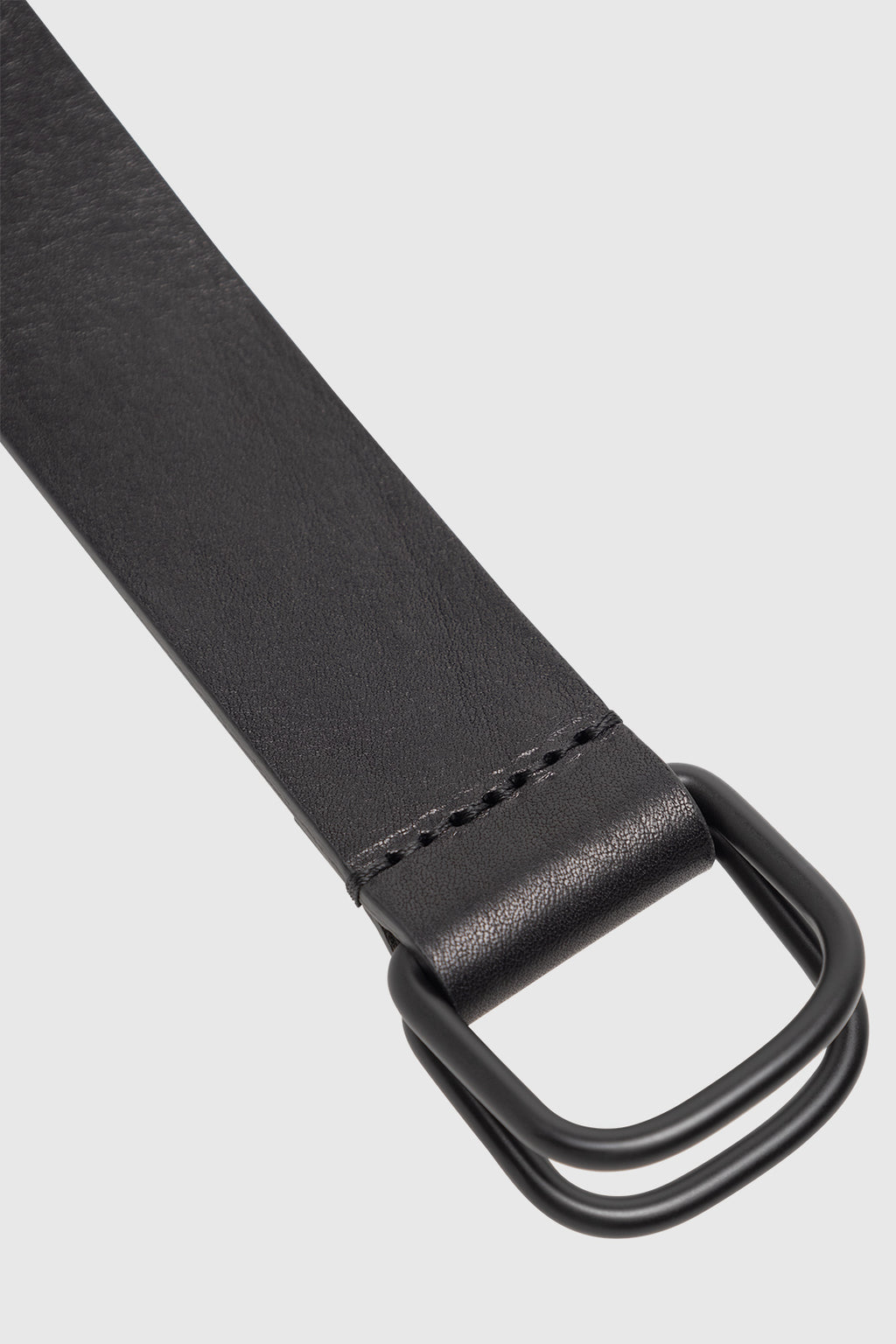 Close-up of the GABmixme Belt - Black by Gabba, highlighting its refined black leather and double black metal D-ring buckle, displayed on a light gray background.