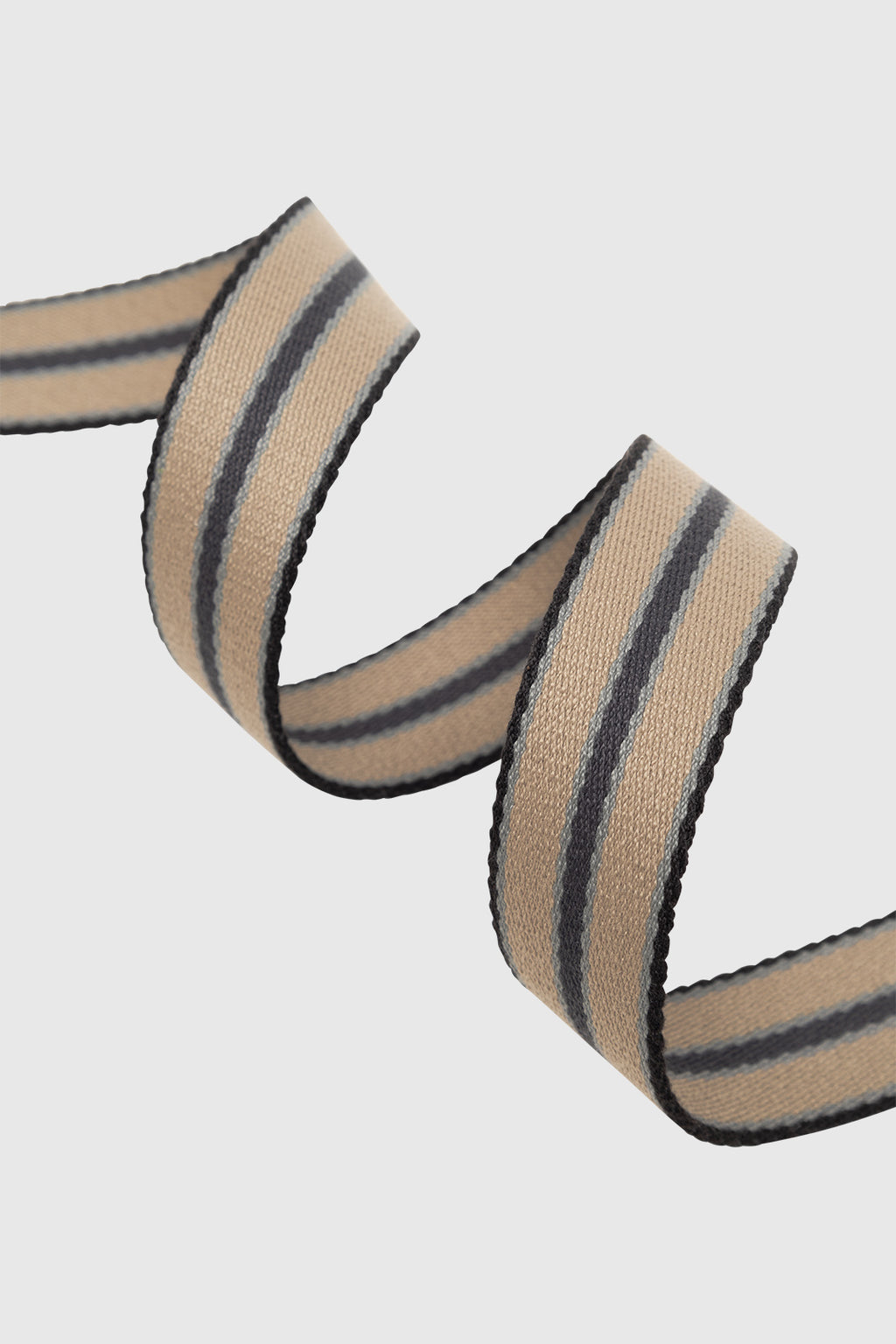 A close-up of the Gabba GABstromboli Belt - Multi Stripe, featuring beige with black and gray stripes, curled in a spiral on a white background to highlight its subtle leather details.