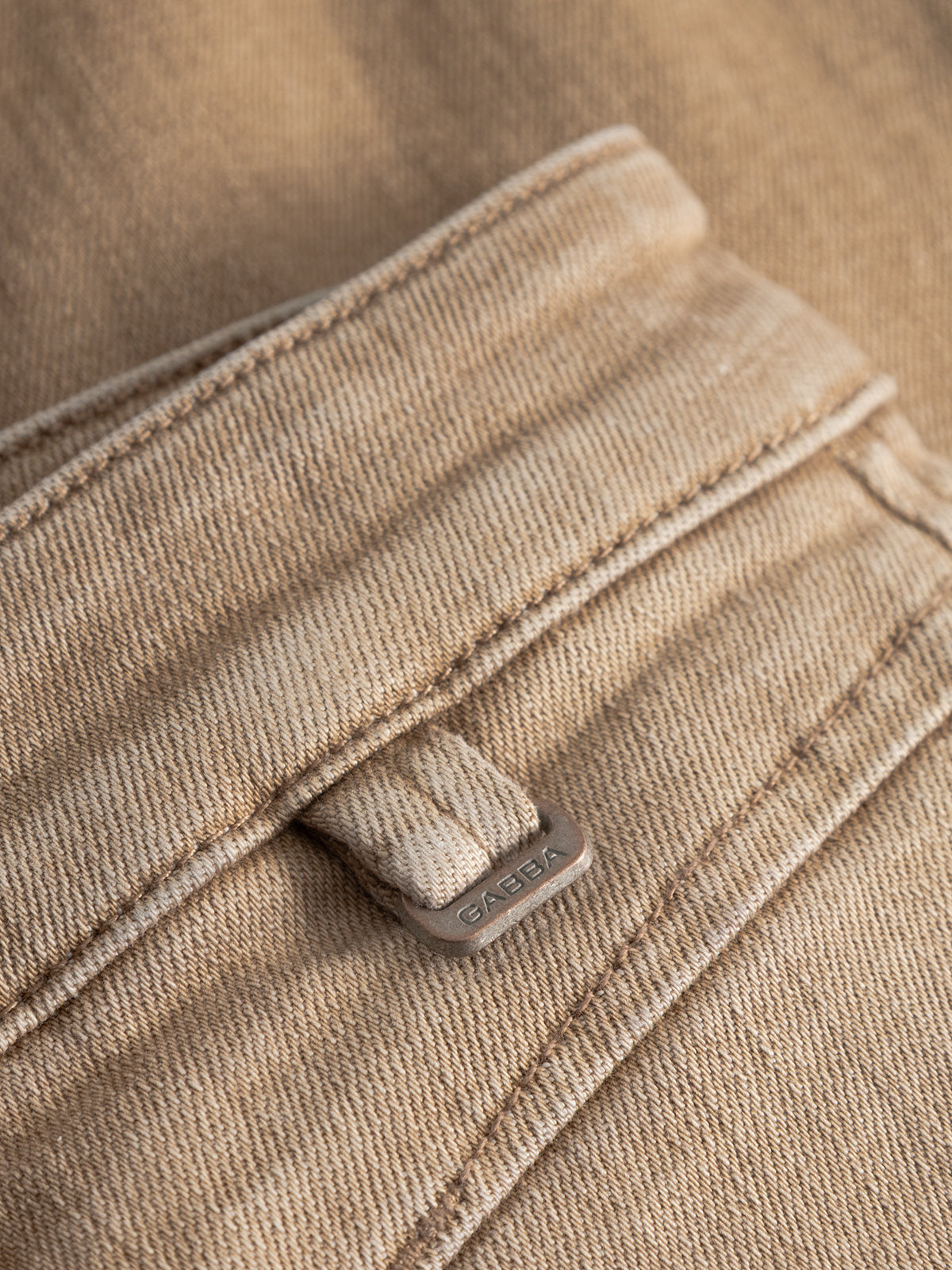 Close-up of the GABalex Earth - Sand relaxed-fit jeans by Gabba, featuring a sand denim pocket with visible stitching and a small metal Gabba tag on a fabric loop near the edge.