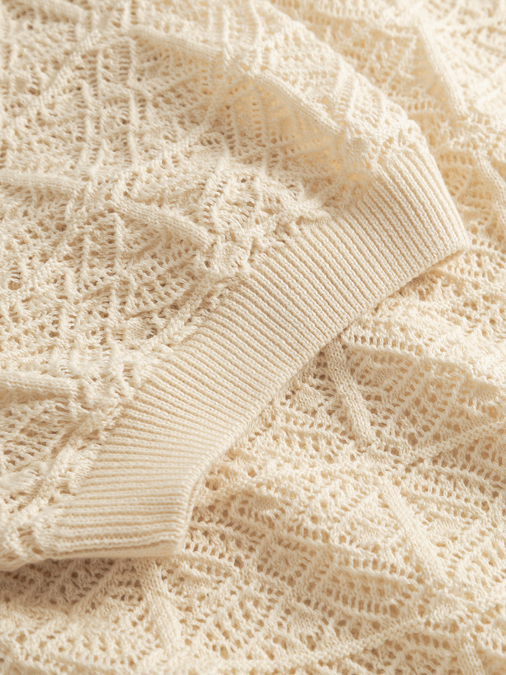 A close-up of the cream-colored knit fabric from the Gabba GABbenson Fiwi SS - Birch, featuring a textured geometric pattern and ribbed cuff, showcasing the brand’s short-sleeve sweater style.