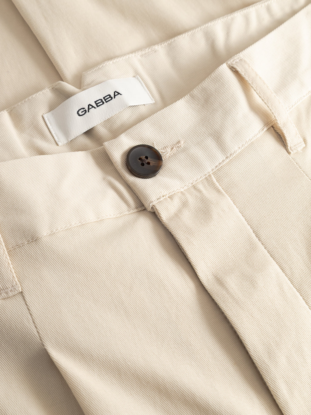 Close-up of Gabba GABfirenze Bolu Cropped TENCEL™ Pant in Birch, featuring a black button at the waistband and a visible white GABBA label inside.