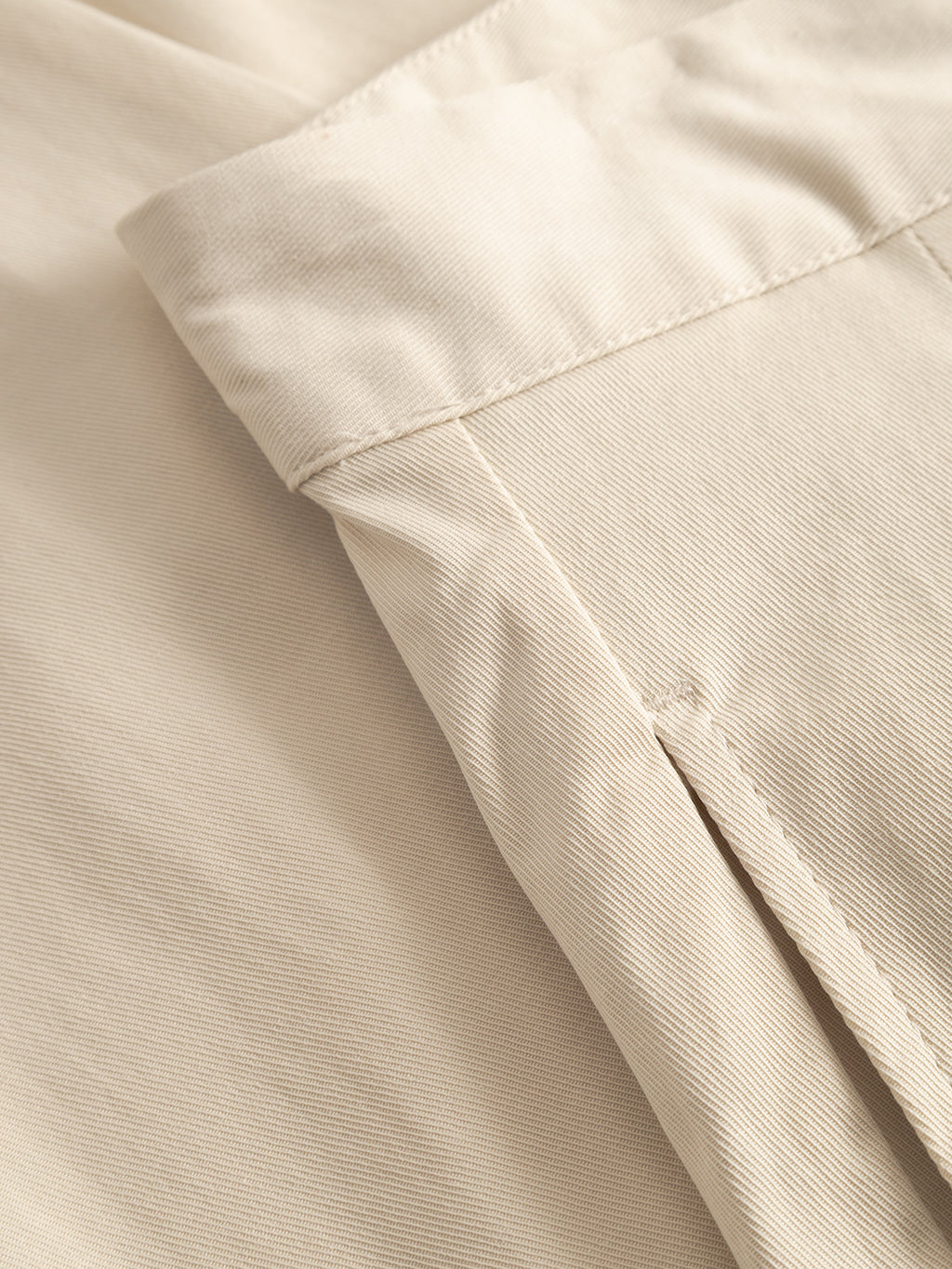 Close-up of the GABfirenze Bolu Cropped TENCEL™ Pant in Birch by Gabba, highlighting the neatly sewn waistband, pleat detail, and visible texture and stitching of the beige fabric.