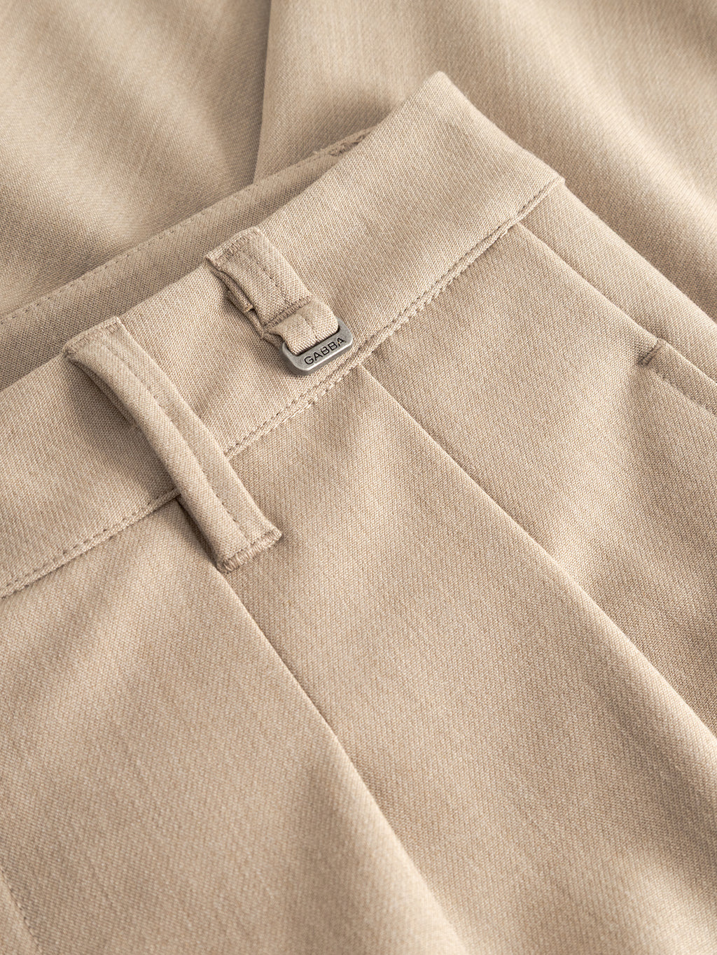 Close-up of Gabba GABfirenze Phin Cropped GRS trousers in Sand Plaza, featuring a belt loop, metal brand tag, and visible stitching on the waistband and pockets.