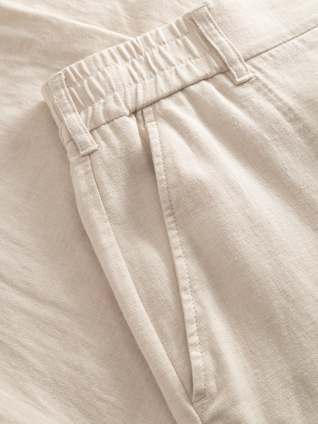Close-up of Gabba's GABzeta Lino - Birch: light beige linen pants crafted from lightweight, breathable fabric, featuring an elastic waistband, belt loops, and a side pocket.