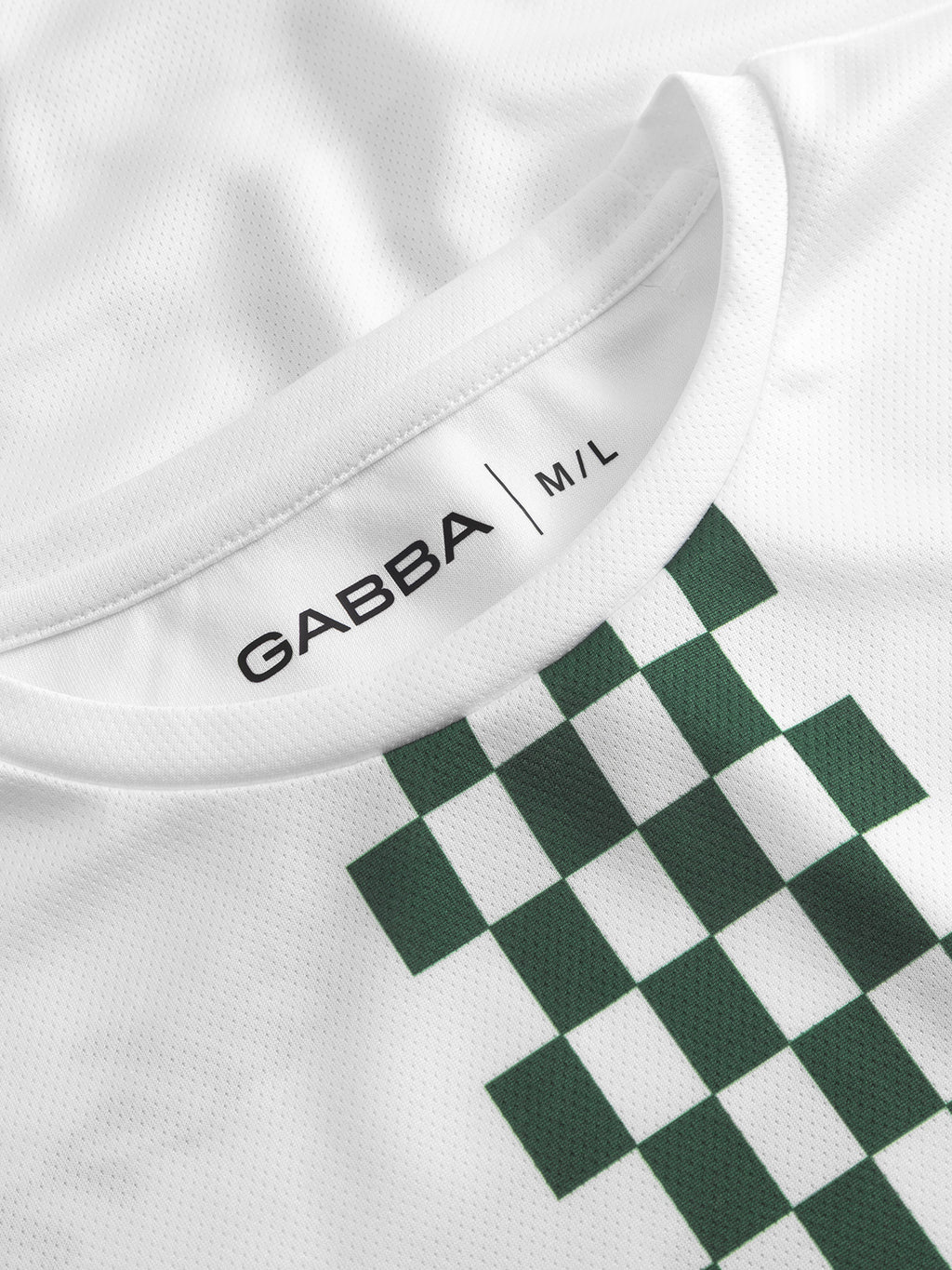 Close-up of the Gabba GABnigel Fut Boxy Pes SS T-shirt in white, featuring a green pixelated checkerboard football-inspired pattern and an inner collar label reading 