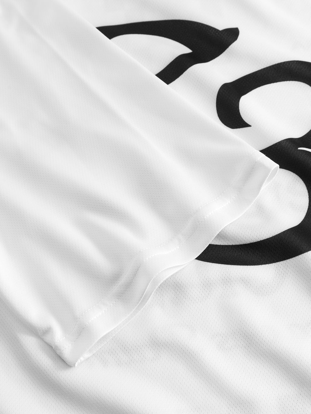 A close-up of the Gabba GABnigel Fut Boxy Pes SS T-shirt in white displays a black printed number partially obscured by the folded sleeve, evoking football culture style.