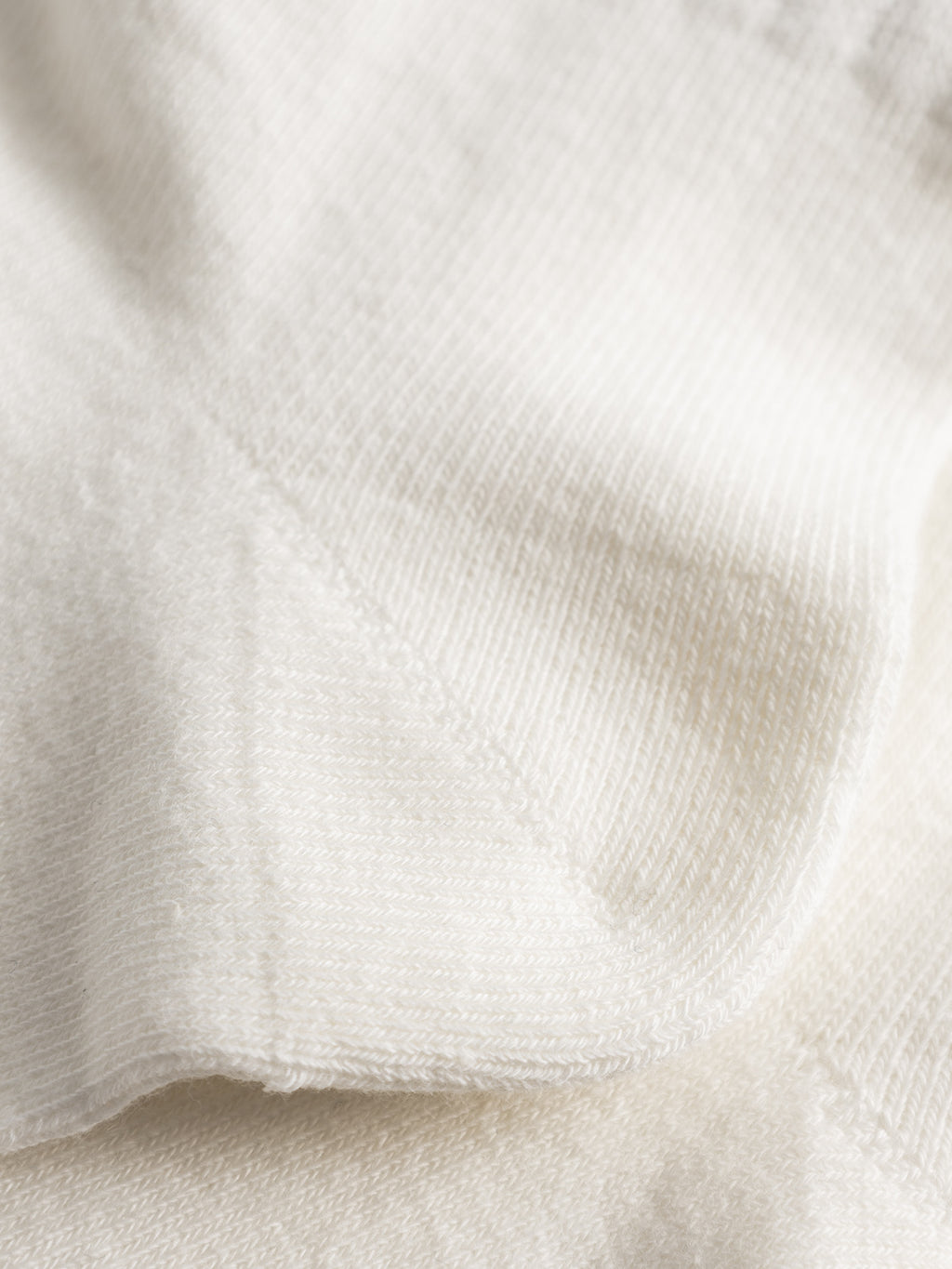 Close-up of soft, white, textured fabric with visible stitching and gentle folds, highlighting the smooth and cozy appearance of Gabba GABbrise Socks - White.