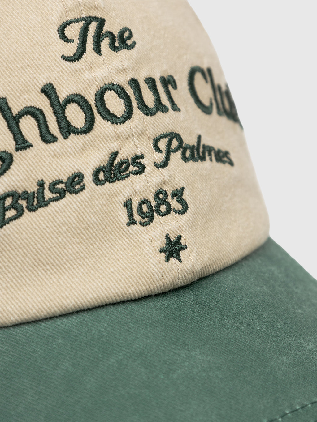 Close-up of the Gabba GABnbh Club Cap - Green, a regular-fit beige and green cap made from soft material, featuring embroidered green text: The Neighbour Club Brise des Palmes 1983, with a small star below the year.