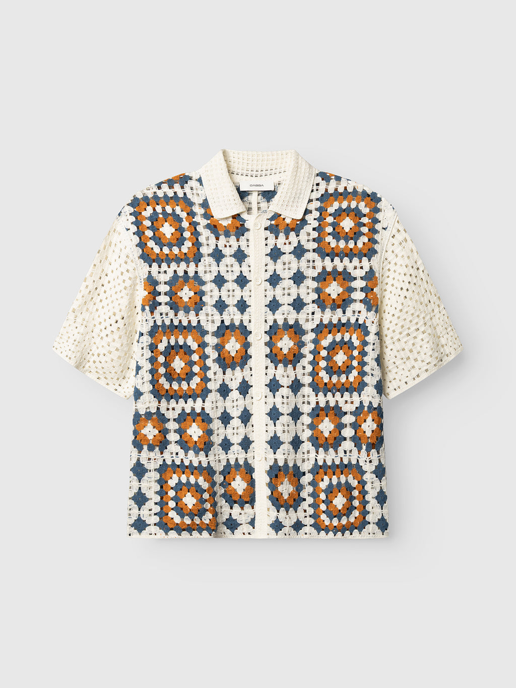 The Gabba GABcrochet Pattern SS Knit - Multi Pattern is a relaxed-fit, short-sleeve collared shirt with navy, orange, and cream crochet squares on the front and cream crochet sleeves and collar—ideal as a unique layering piece.