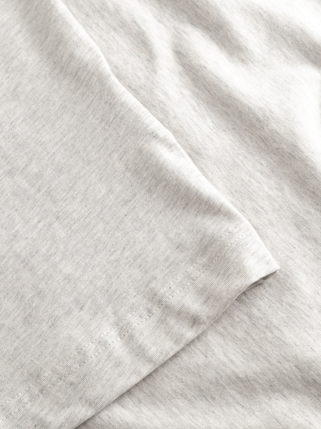 Close-up of Gabba GABdune Melange New SS T-Shirt in Lt. Grey Mel shows soft jersey fabric, visible stitching details, and a slightly folded edge highlighting its smooth texture.
