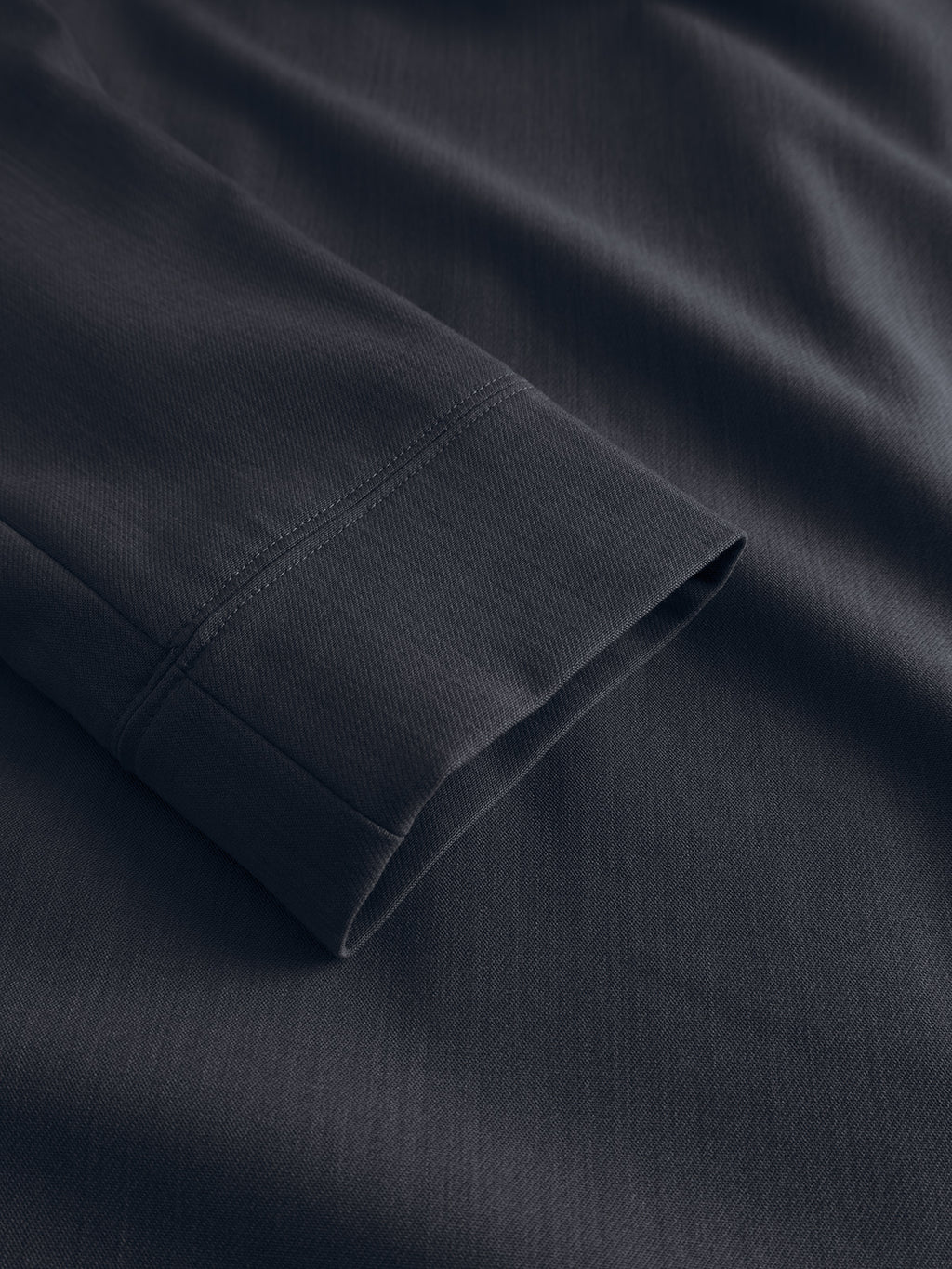 Close-up of the GABnik Phin GRS - Blue Black by Gabba, highlighting the long sleeve's soft, dark recycled polyester fabric with smooth, subtle texture and detailed stitching near the cuff.
