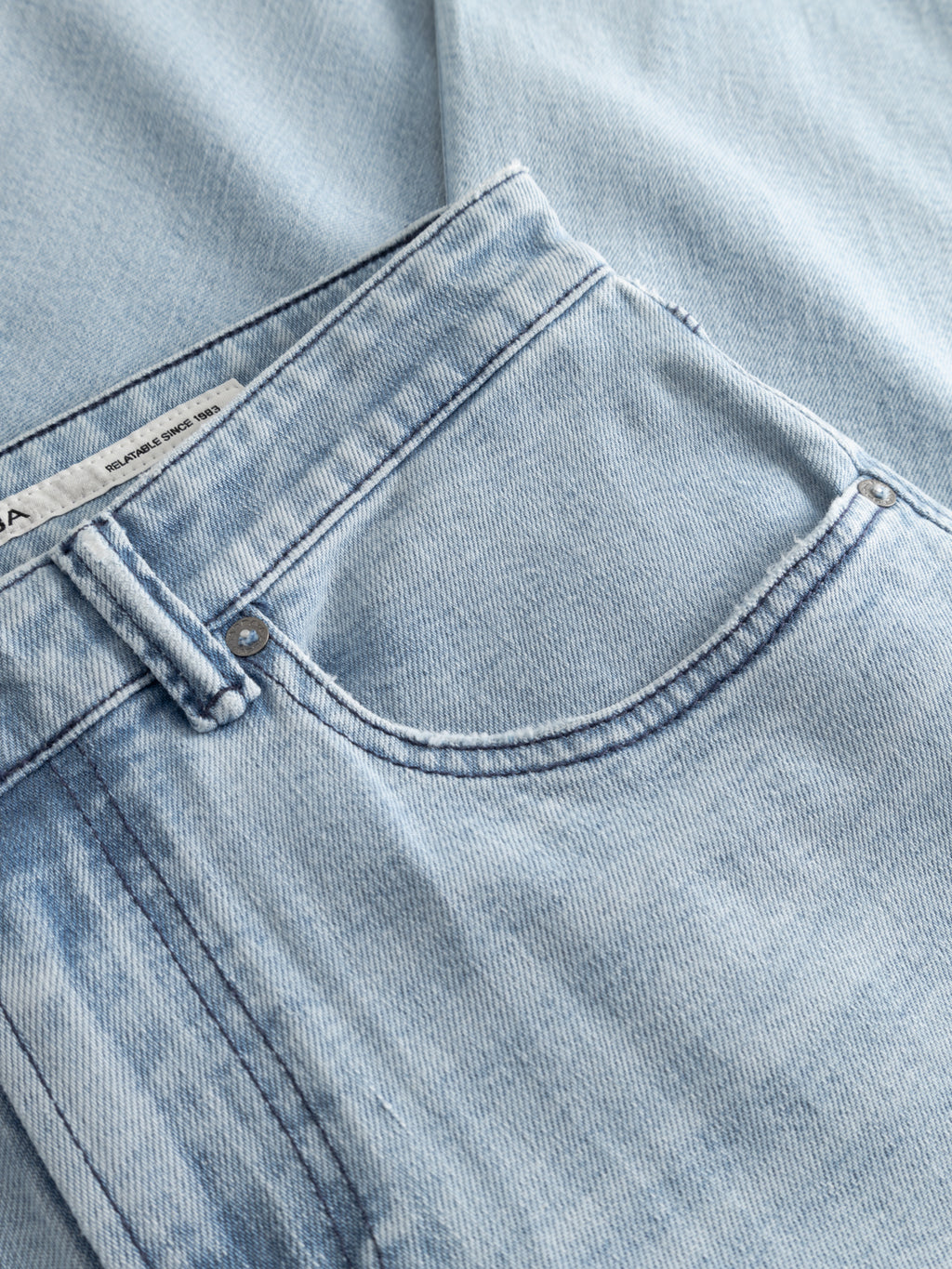 Close-up of Gabba GABcarl Swif Jeans in light blue denim, with front pocket, button, belt loop, branded label on waistband, and comfort stretch fabric featuring a light bleached finish and slightly faded texture.