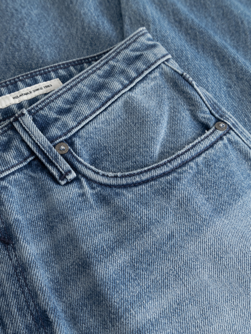 Close-up of Gabba GABmax Elvis Jeans in mid blue denim, featuring a front pocket with visible stitching, two metal rivets, and a partially visible small white fabric label inside.
