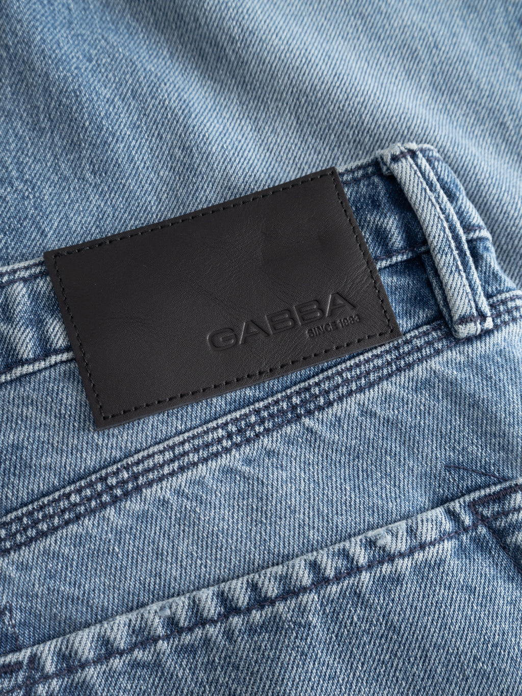 Close-up of GABmax Elvis Jeans by Gabba in mid-blue rigid denim, featuring a black leather patch embossed with 