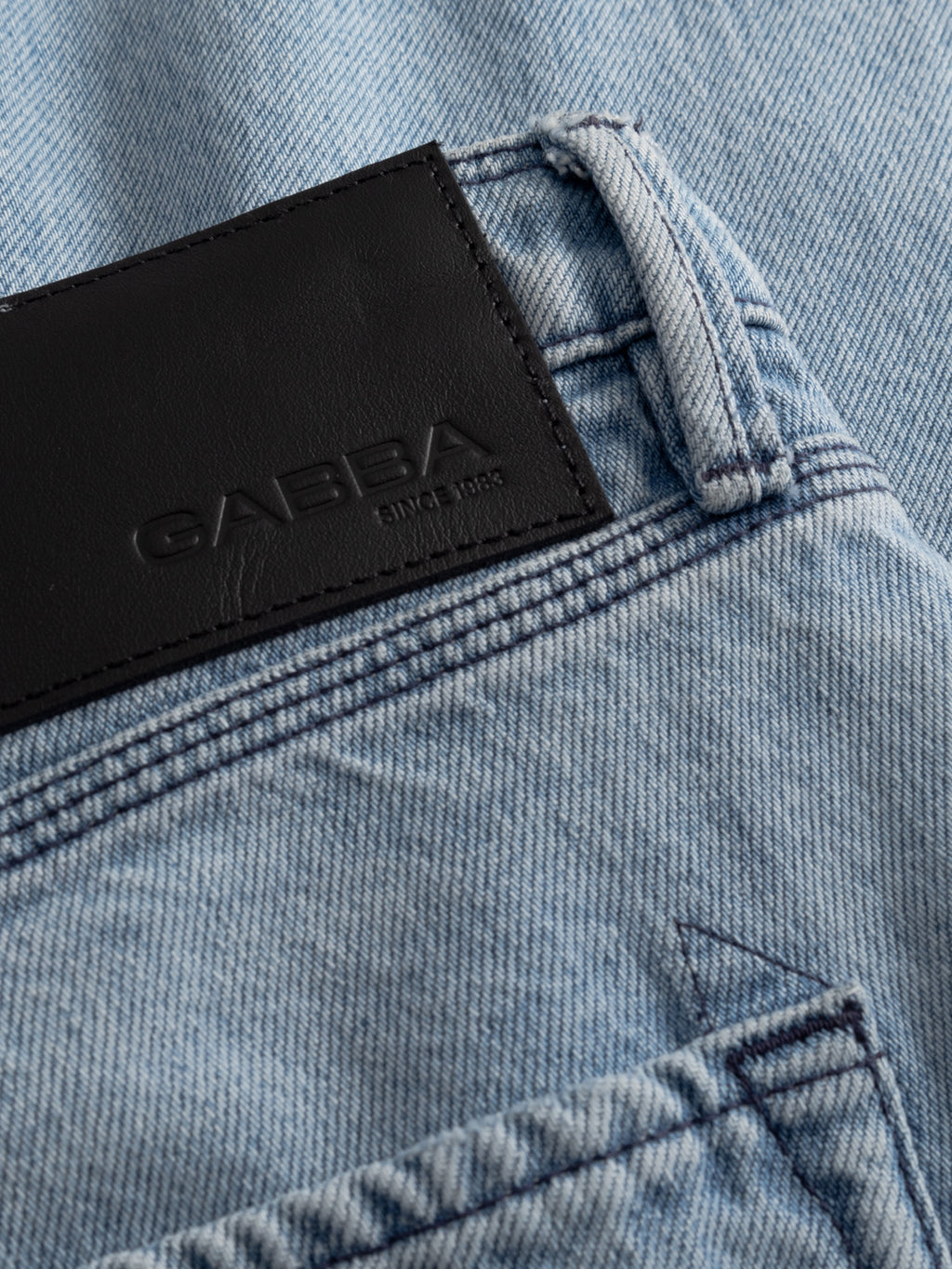 Close-up of Gabba GABmax Elvis Jeans in light blue rigid denim, showcasing a black leather waistband patch embossed with the brand name Gabba and 