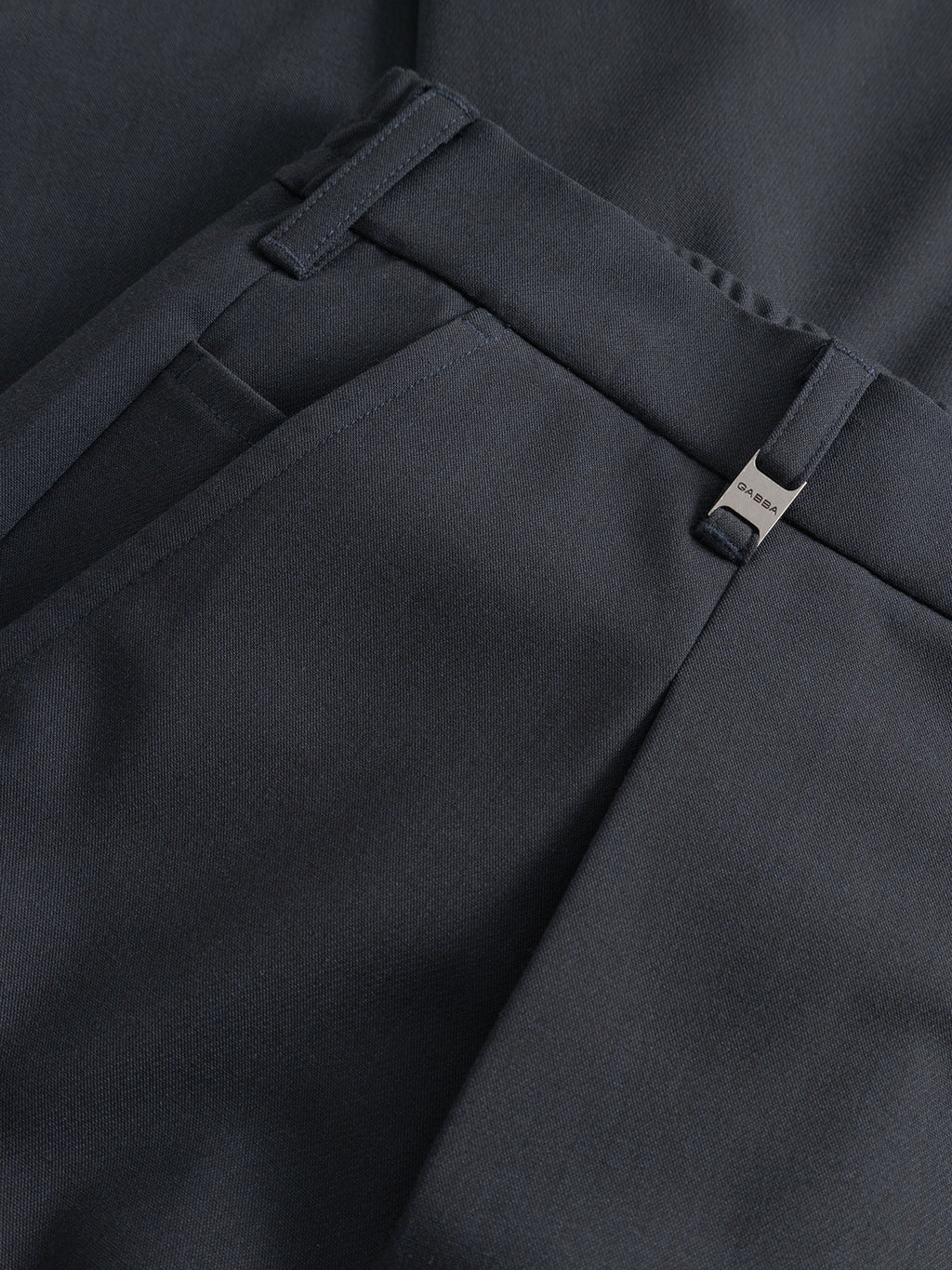 Close-up of Gabba GABnapoli 19 Phin GRS - Blue Black trousers, featuring a smooth wool blend, waistband with belt loops, front pocket, and a small engraved metallic tag. The neatly stitched chinos showcase premium craftsmanship.