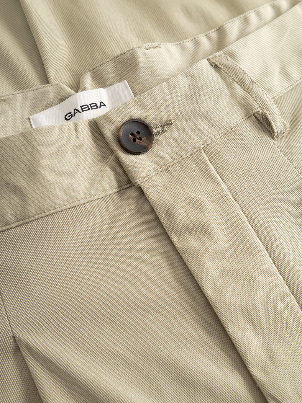 Close-up of Gabba’s GABfirenze Bolu Cropped TENCEL™ Pant in Alfa Green, showcasing the relaxed fit, textured stretch twill fabric, brown button, and visible waistband label.