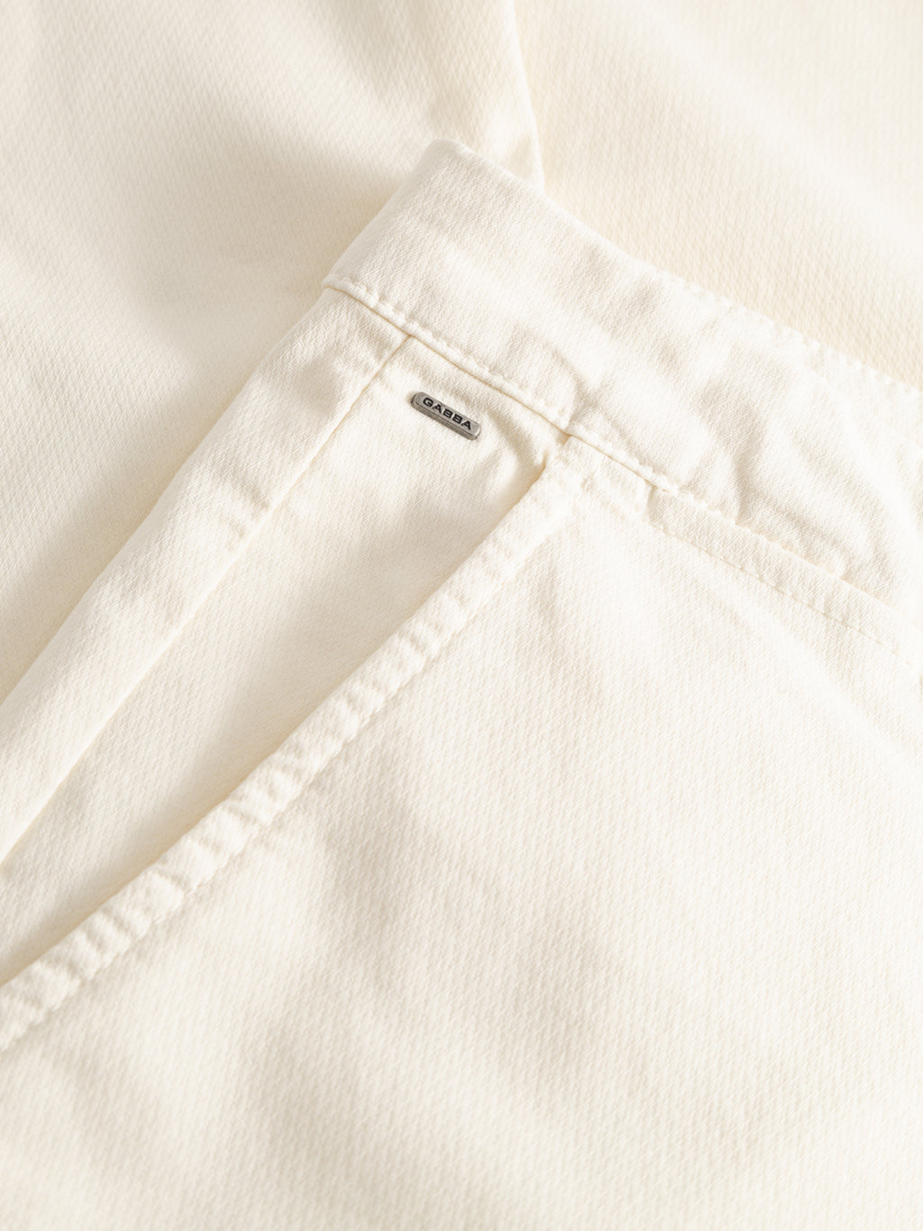 Close-up of the GABpaul K3280 Dale Chino - White by Gabba, showing an off-white cotton pocket with visible stitching and a small ARKEA tag, highlighting the French pockets detail typical of slim chino pants.