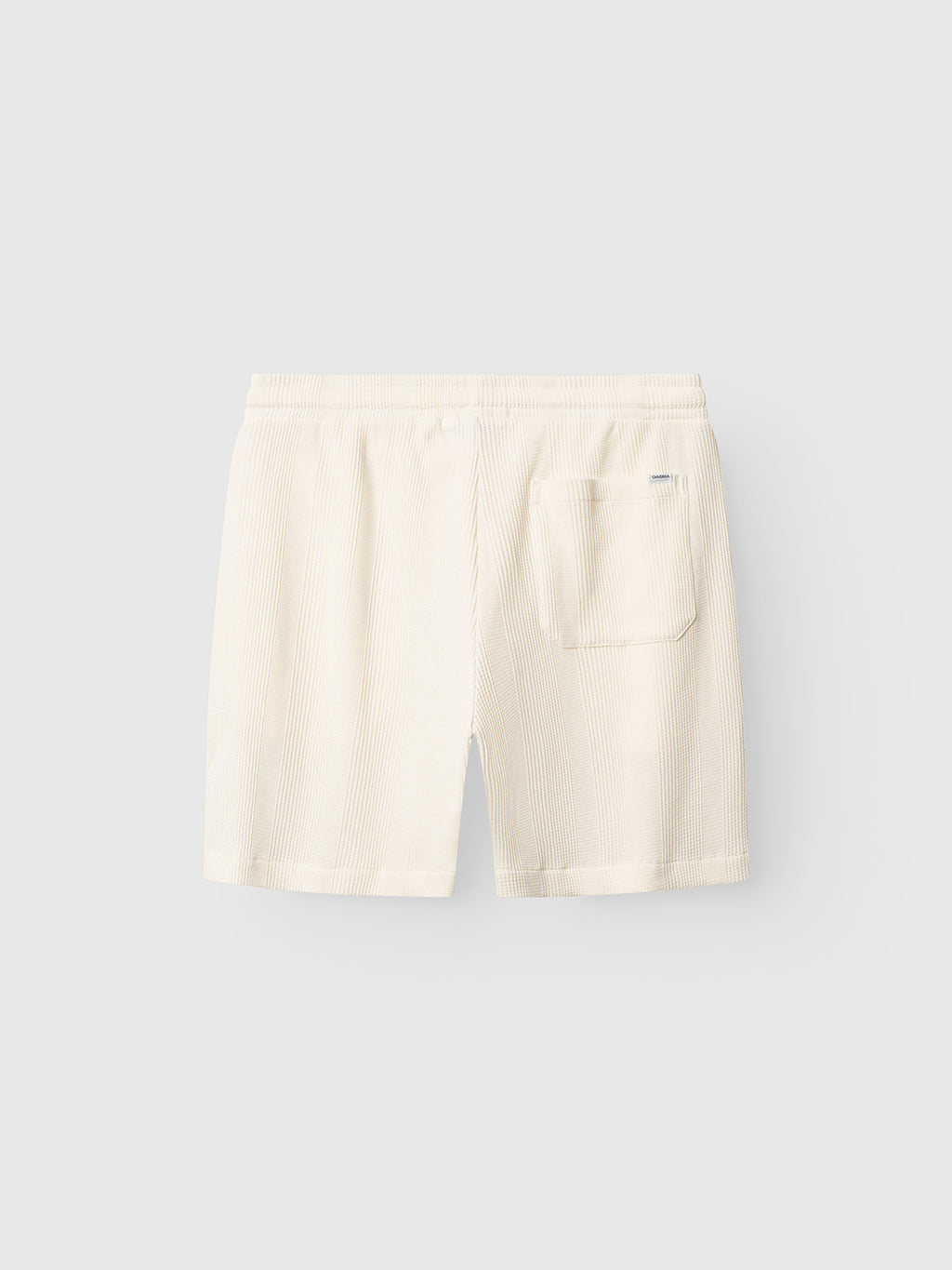 Back view of Gabba GABtommi Wup Shorts in bone white, featuring light pinstripes, a regular fit, comfy waistband, and a single right patch pocket, displayed on a plain light gray background.