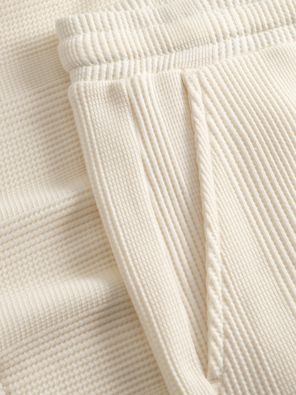 Close-up of GABtommi Wup Shorts - Bone White by Gabba, featuring cream waffle texture, visible waistband with adjustable drawstring, seam details, and side pocket.