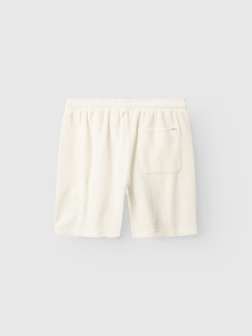 The Gabba GABtommi Towel Shorts in Egret are off-white terry cotton shorts with a regular fit, elastic waistband, and a single back patch pocket, shown against a plain light gray background.
