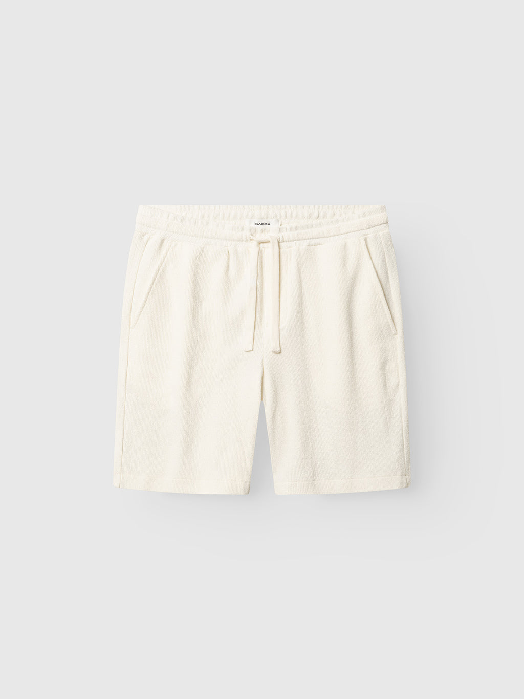 The Gabba GABtommi Towel Shorts - Egret feature off-white terry cotton, an elasticated waistband with drawstring tie, and side pockets, shown against a plain light background.