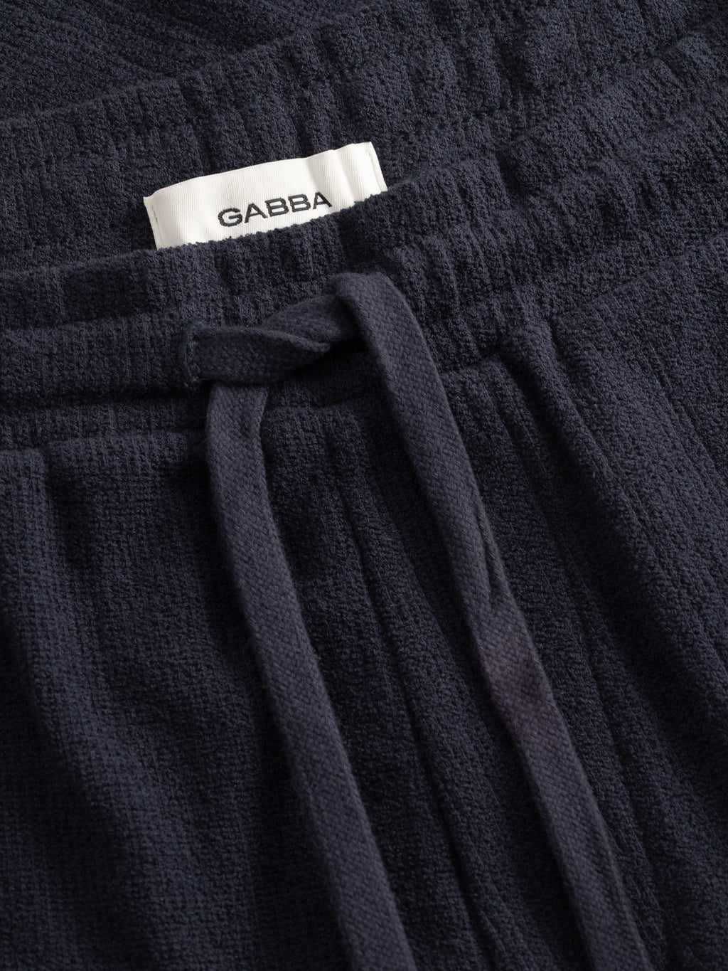 Close-up of GABtommi Towel Shorts in navy by Gabba, featuring a textured terry cotton finish, elastic waistband, and an inner white label with the Gabba brand name.
