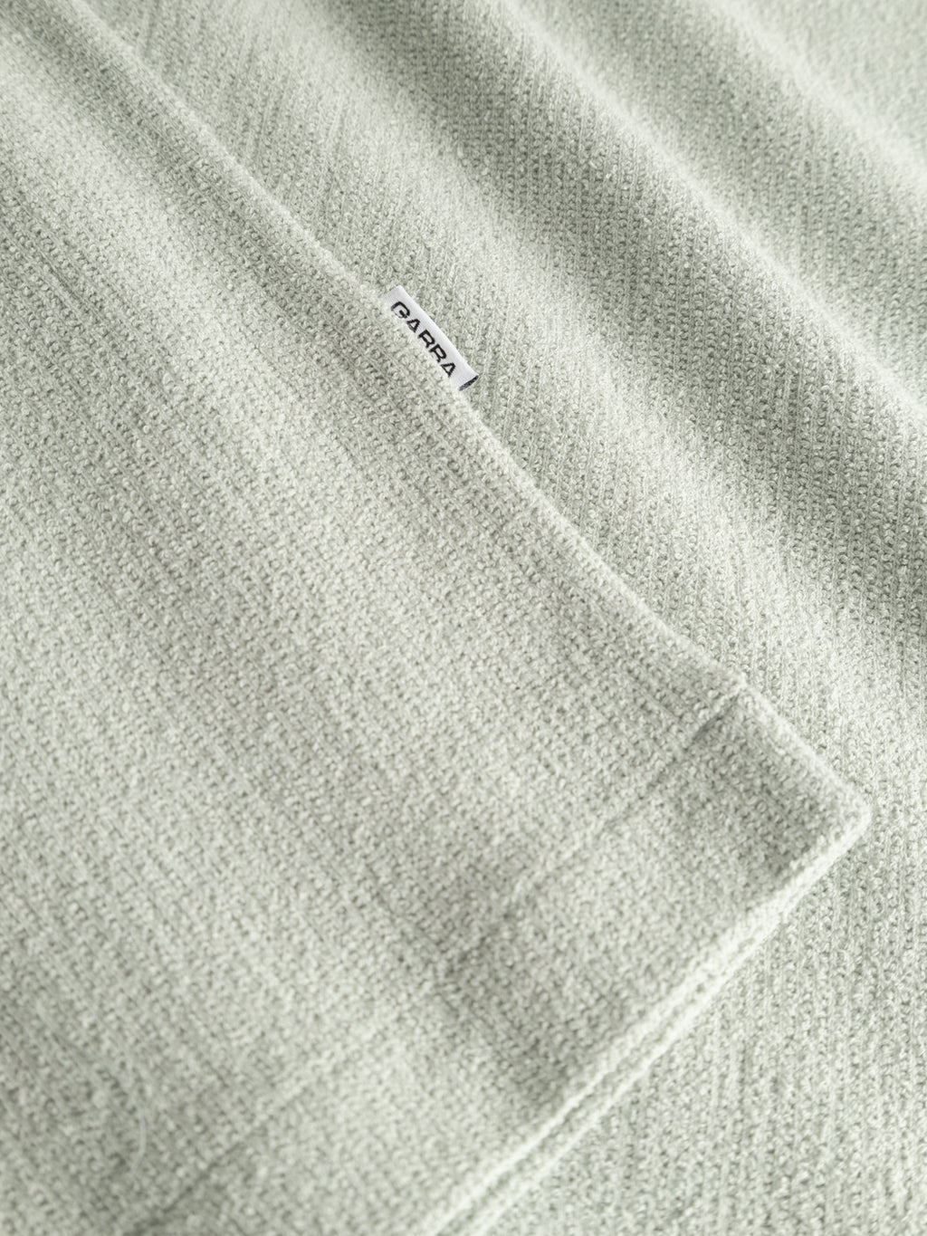 A close-up of the Gabba GABlio Sku Towel T-Shirt in Mineral Gray shows its soft, textured terry cotton fabric and neat stitching, with a small white 