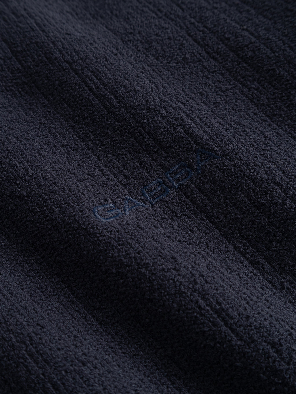Close-up of the GABlio Sku Towel T-Shirt - Night Sky by Gabba, made from textured dark terry cotton blend with soft raised lines. The center features subtle embroidery of 