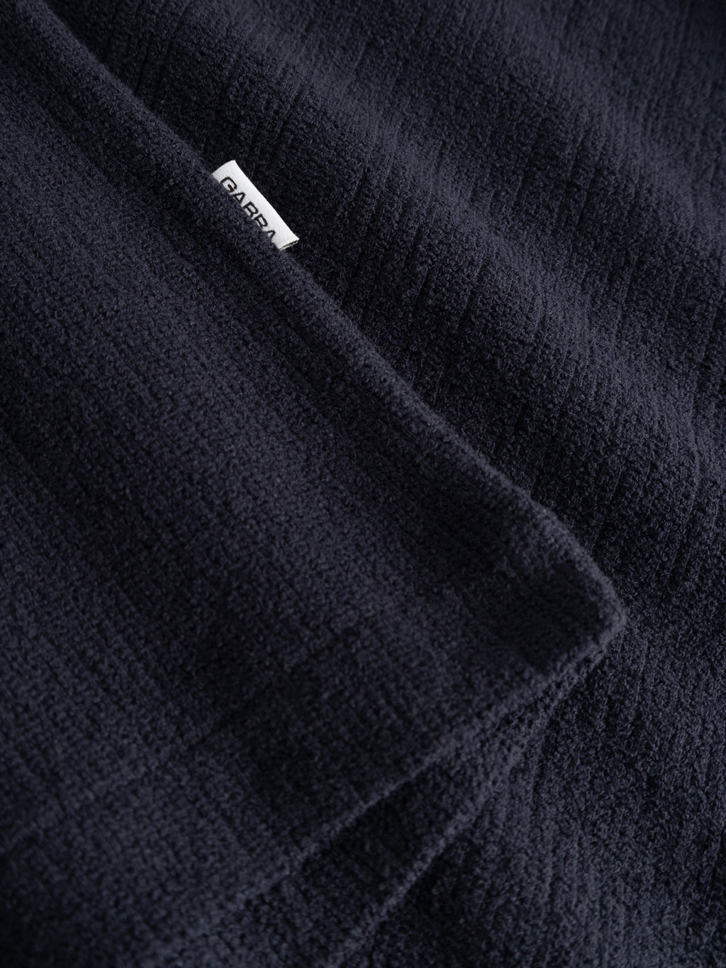 A close-up of the GABlio Sku Towel T-Shirt - Night Sky by Gabba, featuring soft, textured dark navy terry cotton blend fabric and a small white tag with part of the brand name visible.