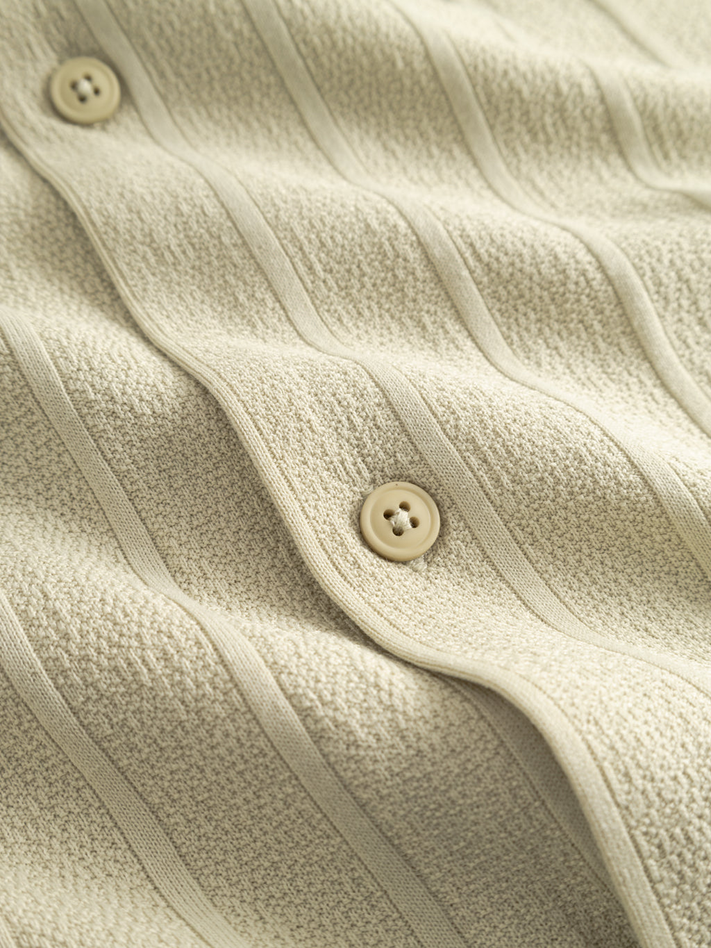 Close-up of the GABvalente Armor SS T-Shirt - Alfa Green by Gabba, featuring textured cotton-blend fabric with vertical ribs and two cream buttons. The wavy surface adds structure, perfect for a relaxed-fit resort collar style.