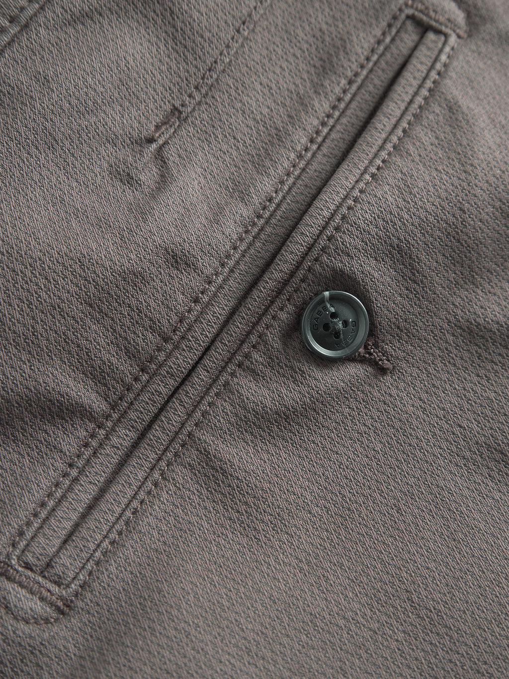 Close-up of the GABpaul K3280 Dale Chino by Gabba in charcoal, featuring a brown textured fabric with a welt pocket and black button—classic style details typical of slim chinos.