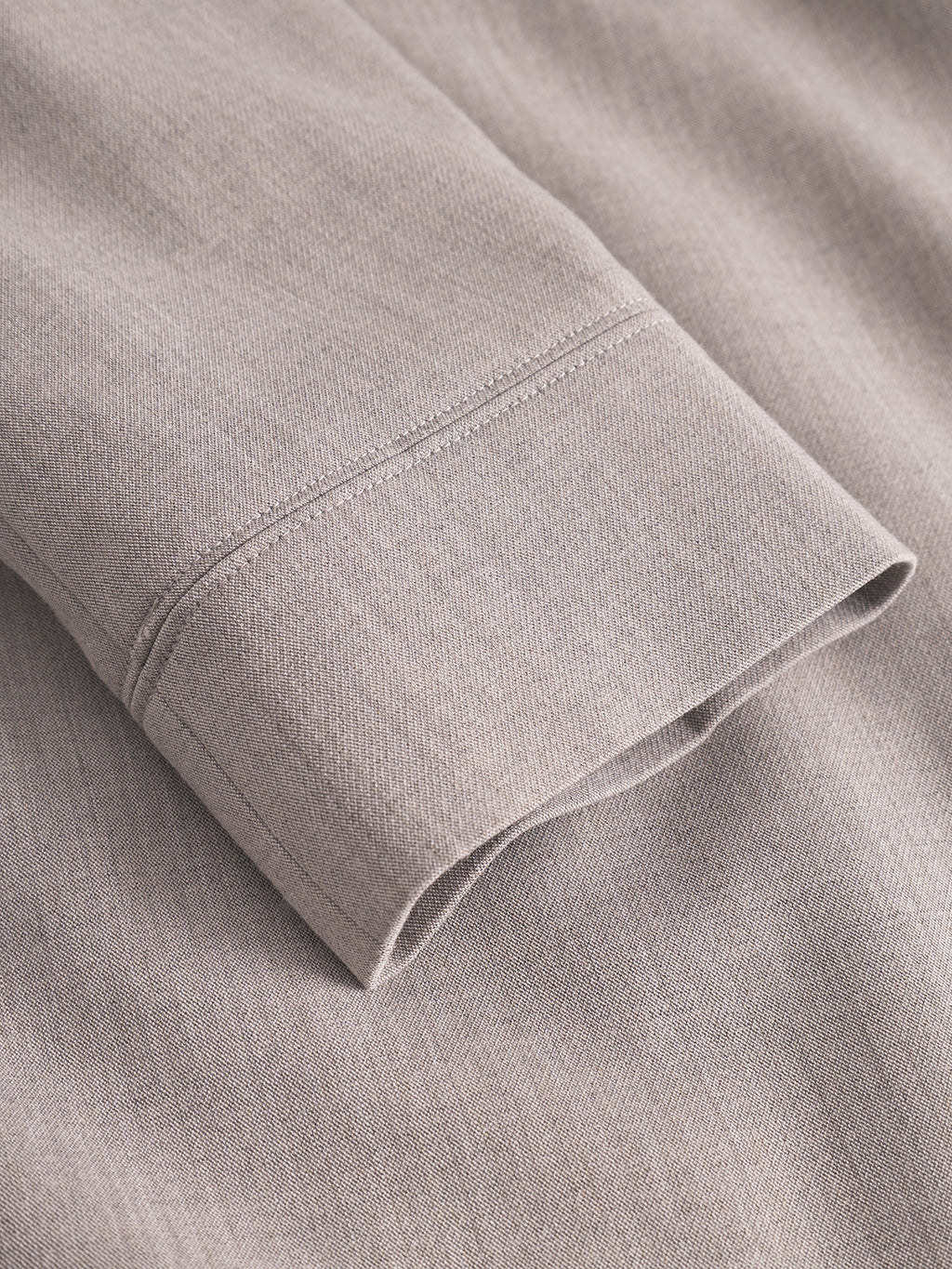 A close-up of the GABnik Phin GRS - Sand shirt sleeve by Gabba, crafted from recycled polyester, highlighting the stitching detail and smooth fabric texture.