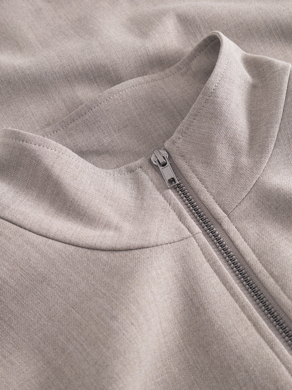 Close-up of the Gabba GABnik Phin GRS - Sand jacket, crafted from GRS-recycled polyester in light beige, with a visible metal zipper and folded collar highlighting its texture and precise stitching.
