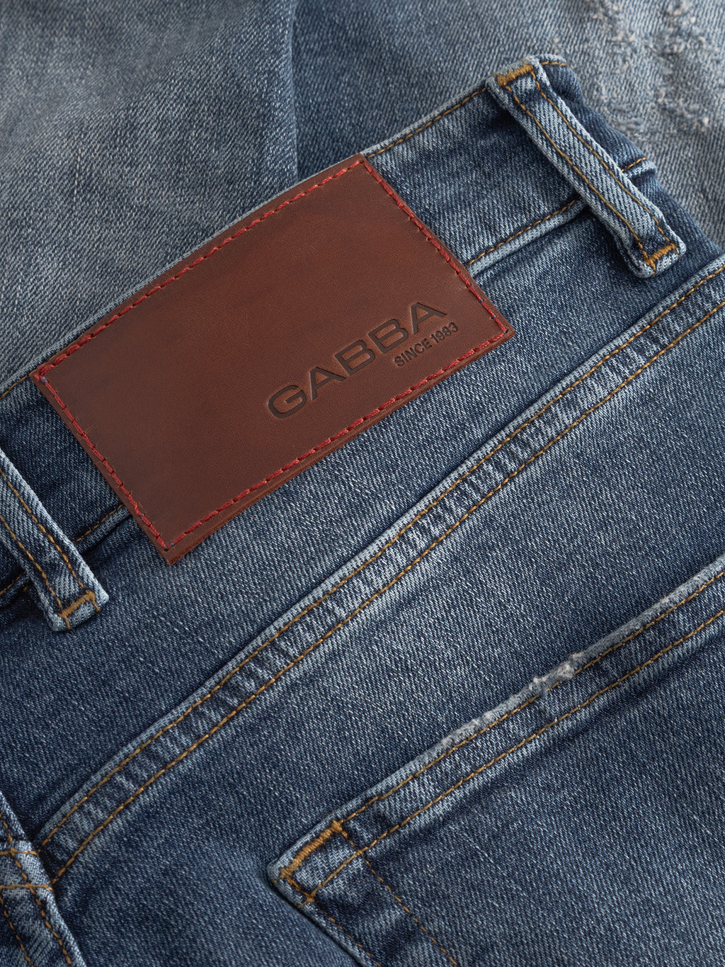 Close-up of Gabba’s GABalex Cros Cropped jeans in mid blue denim with a brown leather patch embossed with the brand and “Since 1983.” Made from recycled cotton, these feature visible stitching, pocket details, and premium cross-hatch fabric.