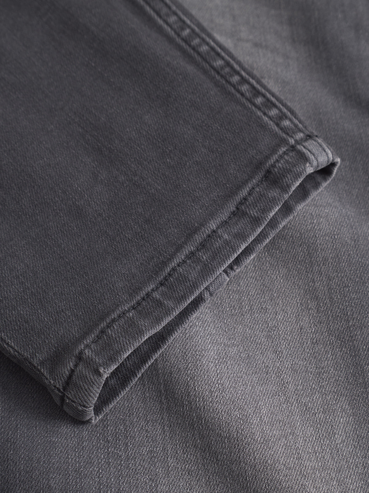 Close-up of the hem on GABBA’s GABalex Thor Cropped Jeans in denim wash, highlighting intricate stitching and fabric texture, with the jeans laid flat to showcase their fashion-forward fit and design details.