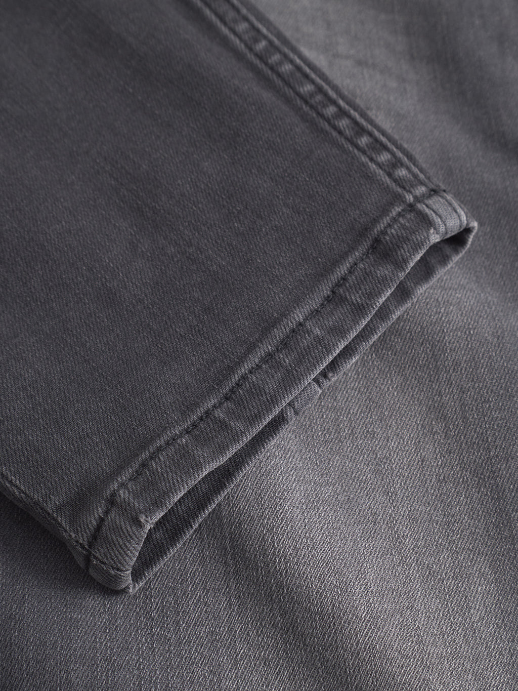 Close-up of the hem on GABBA’s GABalex Thor Cropped Jeans in denim wash, highlighting intricate stitching and fabric texture, with the jeans laid flat to showcase their fashion-forward fit and design details.