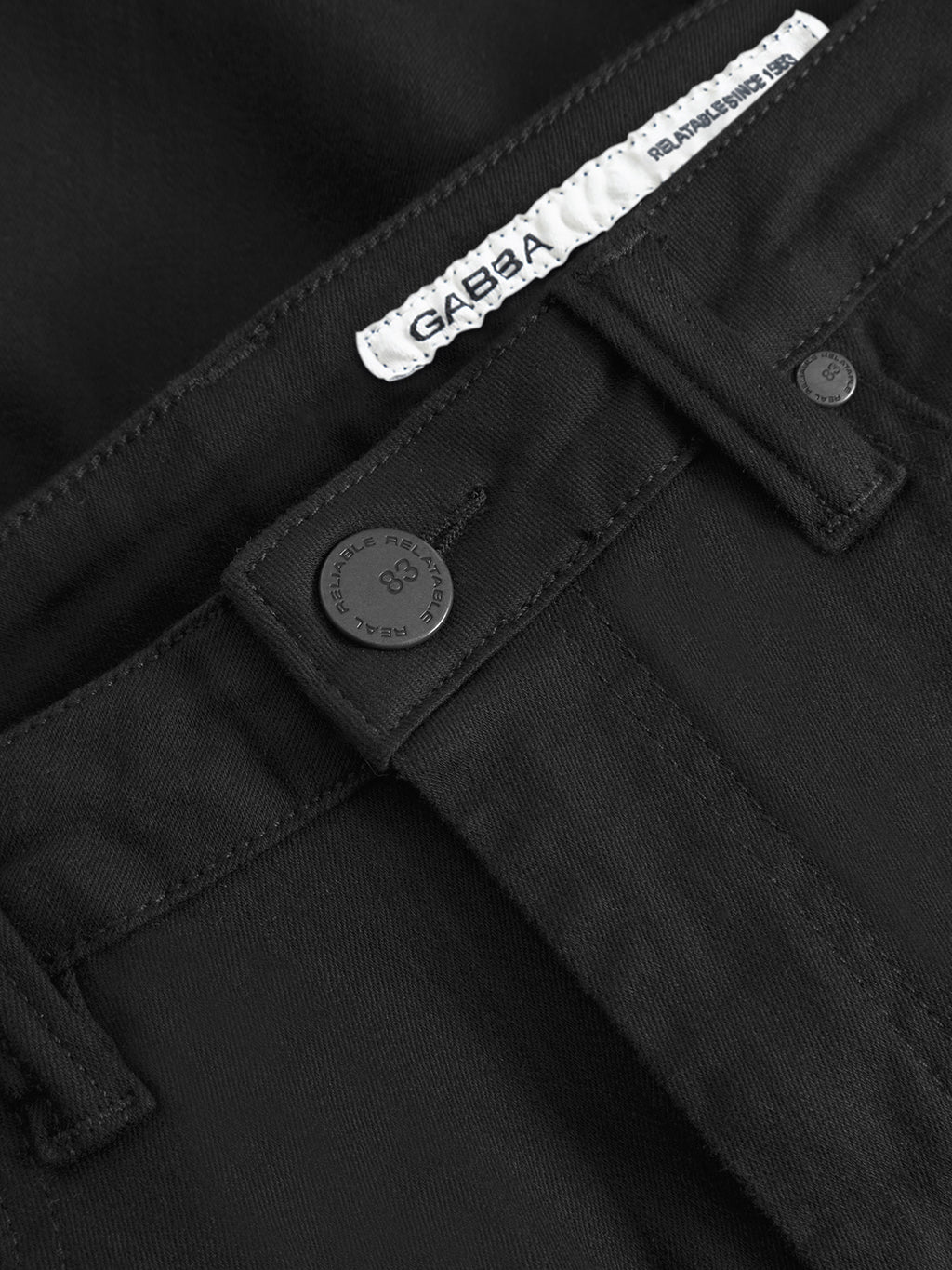 Close-up of the waistband of GABjones Hold Black - Black Denim jeans, showing a black button, belt loops, and a white Gabba label inside, made from high-flexibility super-stretch fabric.