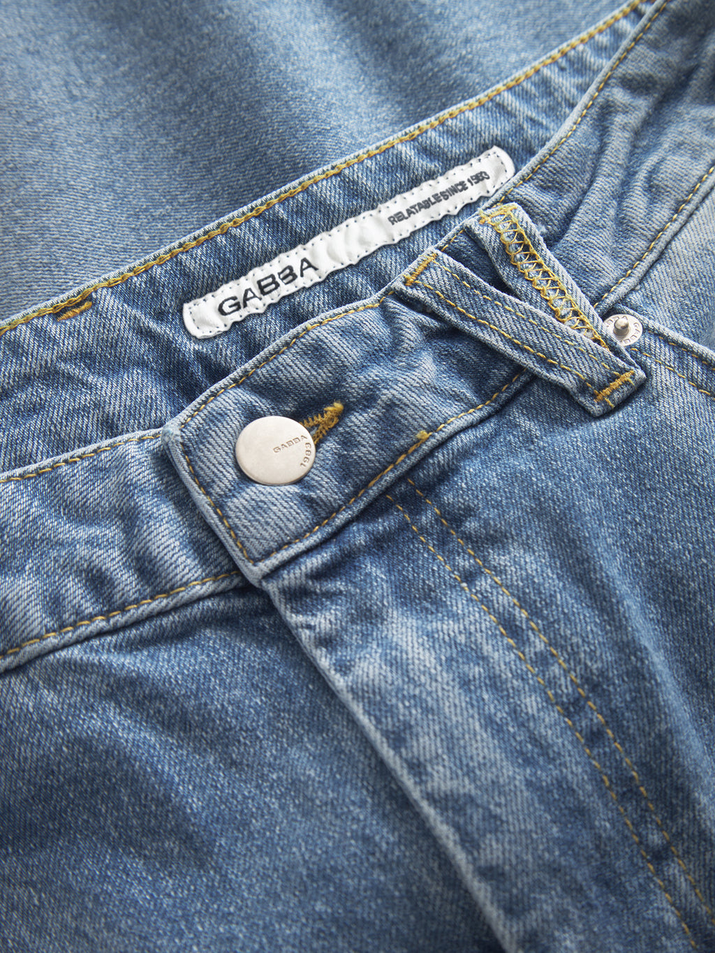 Close-up of Gabba GABMarc 5poc - Mid Blue Denim jeans with a metallic button, belt loops, yellow stitching, slight fading, and a visible white 