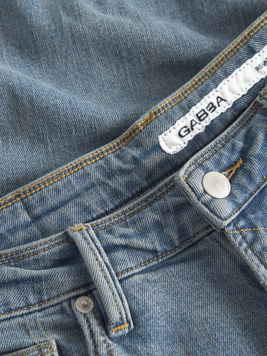 Close-up of GABmax Cros - Lt. Blue Denim jeans by Gabba, featuring a button, belt loops, fine stitching, and a white inner label for a sharp look and modern slim fit.