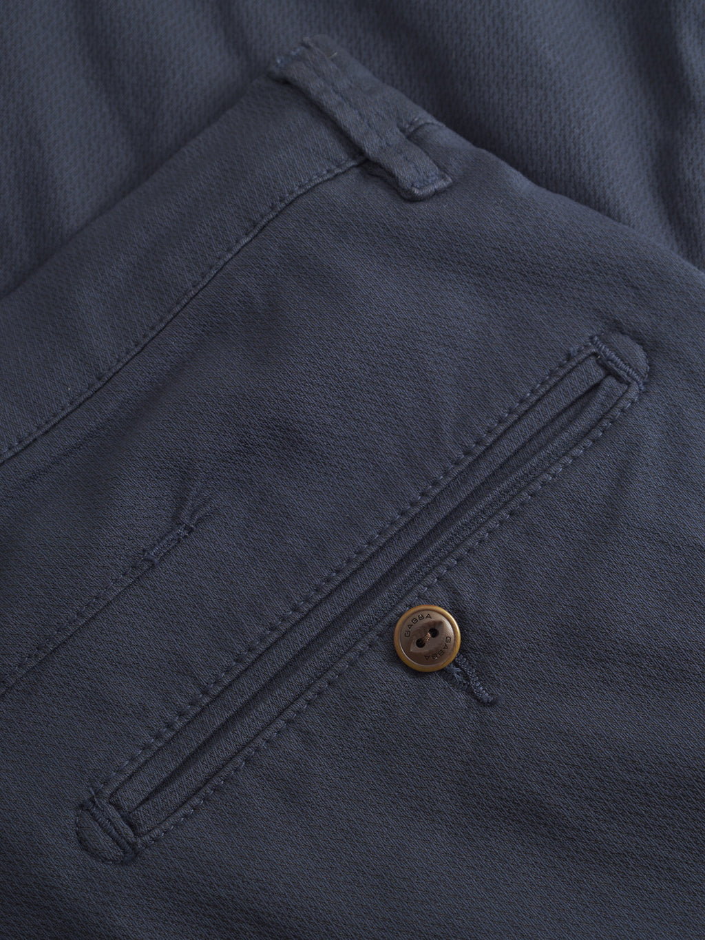 Close-up of the back pocket on GABBA’s GABpaul K3280 Dale Chino - Navy, showing a horizontal zipper and brown button. The textured fabric, visible stitching, and French pockets highlight its tailored design.